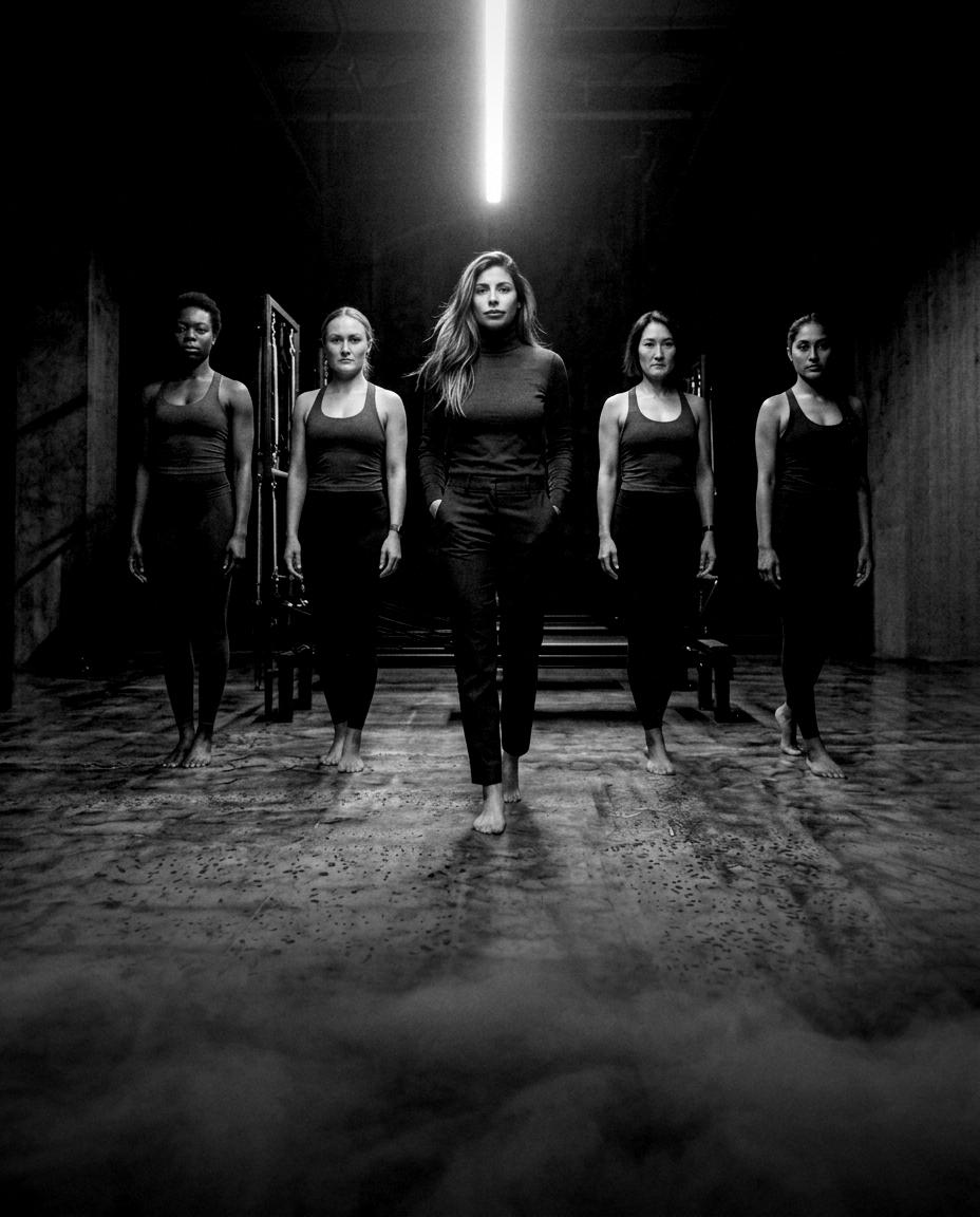 Sana Badhwar leading a formation of Pilates instructors in a dark studio